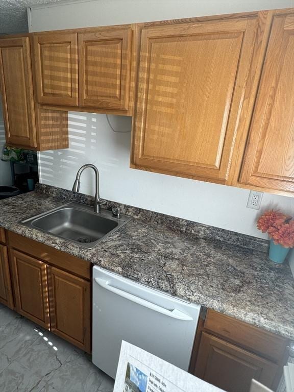 kitchen with white dishwasher, a sink, marble finish floor, brown cabinetry, and dark countertops