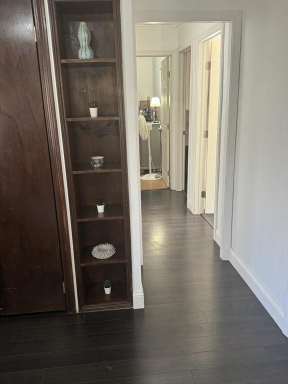 hall with dark wood-style floors and baseboards