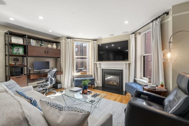 living room featuring a fireplace with flush hearth, recessed lighting, and wood finished floors