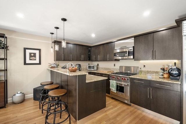 kitchen featuring a breakfast bar area, dark brown cabinets, light wood-style floors, and appliances with stainless steel finishes