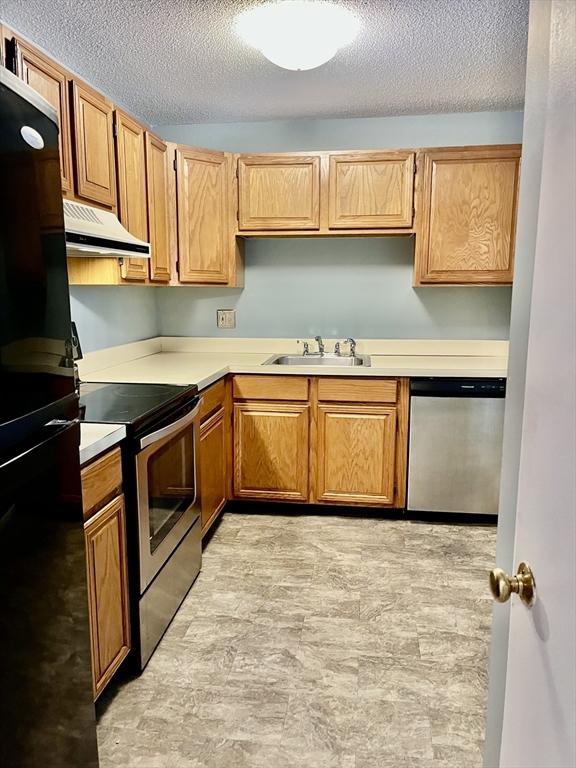 38 Dunham Rd Unit 303, Beverly, MA 01915 - kitchen featuring stainless steel appliances, under cabinet range hood, a sink, a textured ceiling, and light countertops