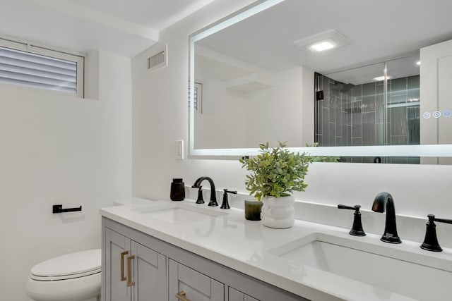 bathroom featuring a tile shower, vanity, and toilet