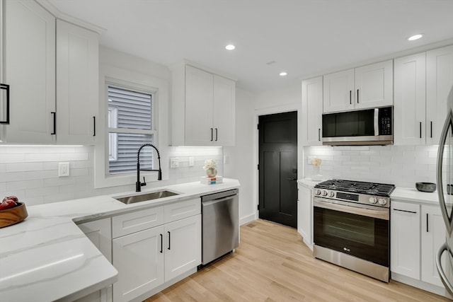 kitchen with white cabinetry, sink, light hardwood / wood-style flooring, and stainless steel appliances