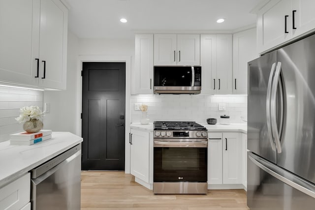 kitchen featuring light stone counters, white cabinets, light hardwood / wood-style flooring, decorative backsplash, and appliances with stainless steel finishes