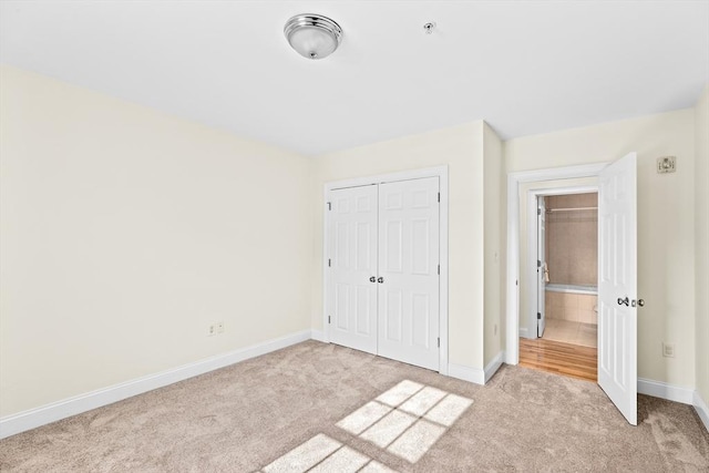 unfurnished bedroom with light colored carpet and a closet