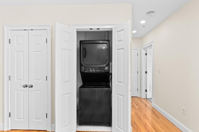 laundry area featuring hardwood / wood-style flooring and stacked washer / dryer