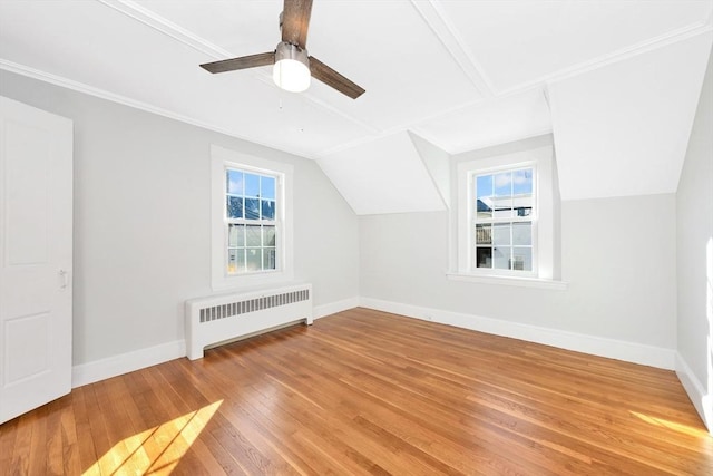 additional living space with hardwood / wood-style flooring, ceiling fan, radiator heating unit, and vaulted ceiling