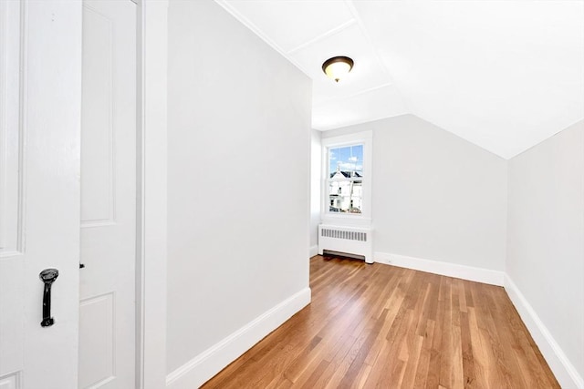 additional living space featuring lofted ceiling, radiator heating unit, and light hardwood / wood-style flooring