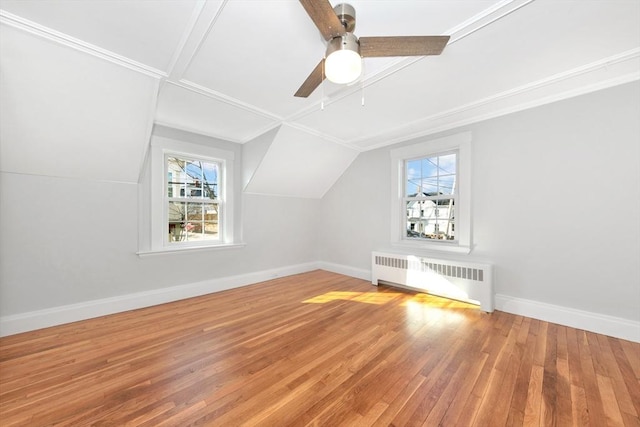 additional living space with hardwood / wood-style flooring, lofted ceiling, radiator heating unit, and ceiling fan