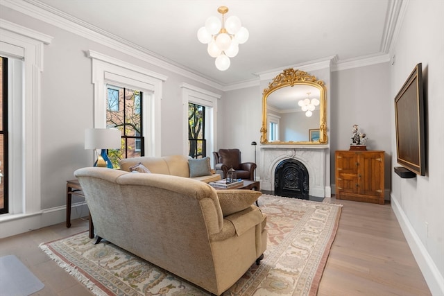 living room featuring an inviting chandelier, light wood-type flooring, a premium fireplace, and ornamental molding