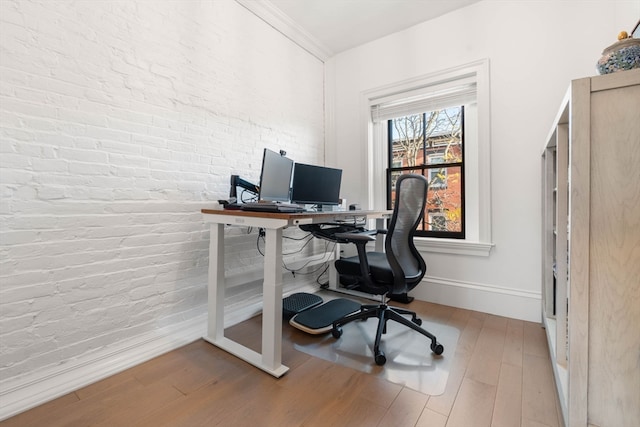 office space with hardwood / wood-style floors, ornamental molding, and brick wall