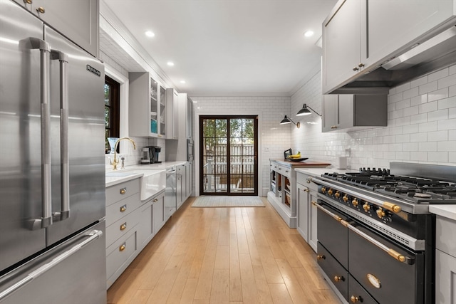 kitchen featuring sink, backsplash, gray cabinetry, light hardwood / wood-style flooring, and high quality appliances