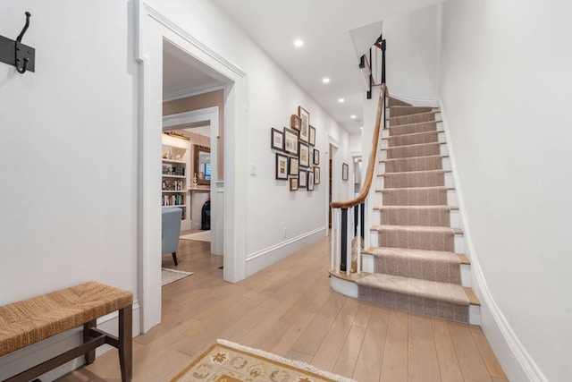 stairs with wood-type flooring and ornamental molding