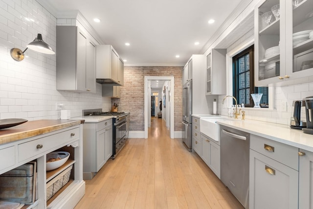 kitchen featuring light hardwood / wood-style floors, sink, high end appliances, crown molding, and gray cabinetry