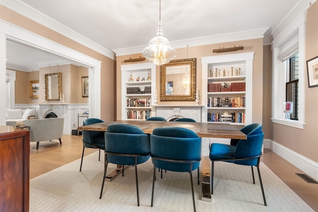 dining space featuring light wood-type flooring, built in shelves, and ornamental molding