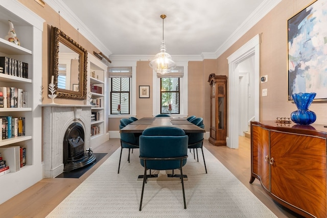 dining room with built in features, ornamental molding, and light hardwood / wood-style flooring