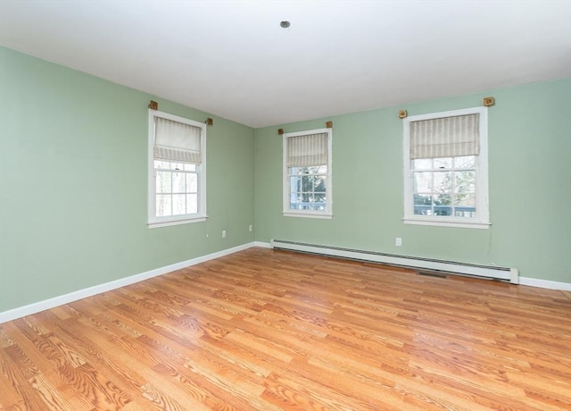 spare room with baseboard heating, baseboards, and wood finished floors