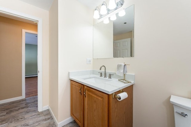 half bath with baseboards, toilet, wood finished floors, vanity, and a baseboard radiator