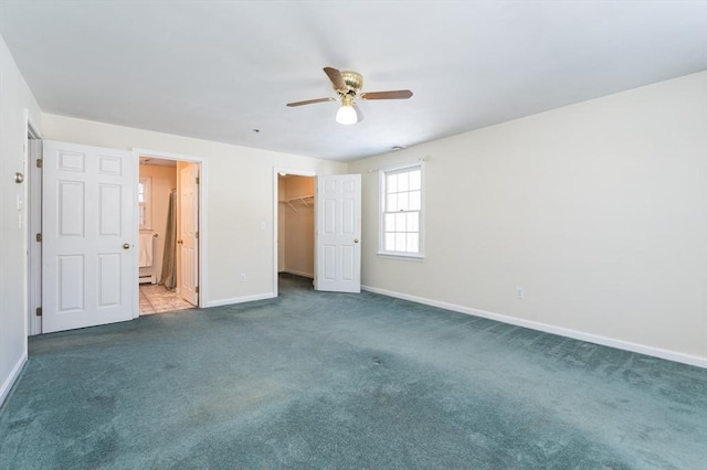 unfurnished bedroom with a closet, baseboards, carpet, and a spacious closet