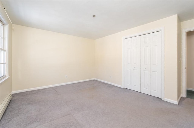 unfurnished bedroom with a baseboard radiator, multiple windows, and carpet