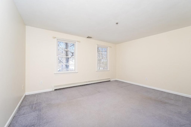 carpeted spare room with a baseboard heating unit, baseboards, and visible vents