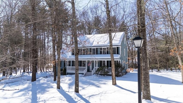 snow covered house featuring a porch