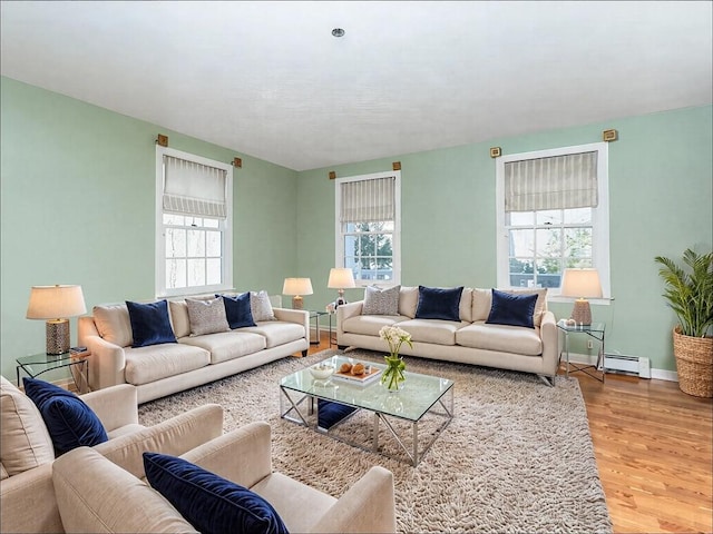 living area with a baseboard radiator, wood finished floors, baseboards, and a healthy amount of sunlight