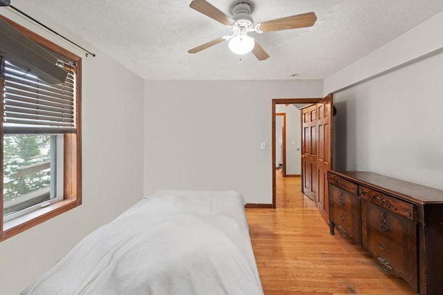 bedroom featuring ceiling fan, light wood-type flooring, and a textured ceiling