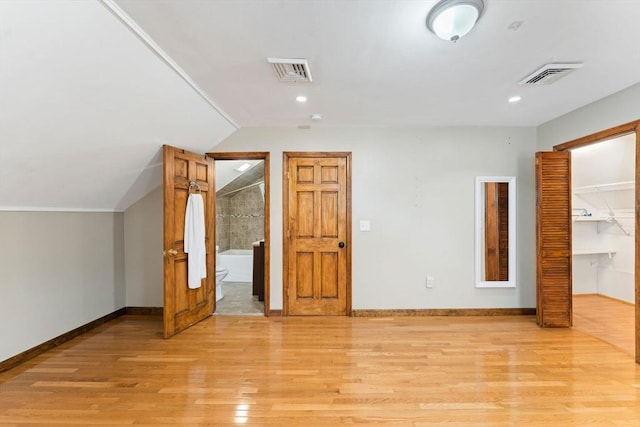 additional living space featuring lofted ceiling and light hardwood / wood-style flooring