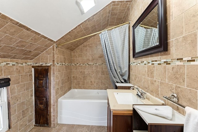 bathroom featuring shower / bath combination with curtain, tile walls, vanity, and vaulted ceiling