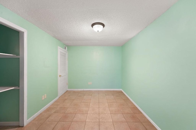 unfurnished room with a textured ceiling and light tile patterned floors