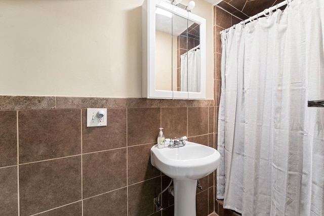 bathroom with a shower with shower curtain and tile walls