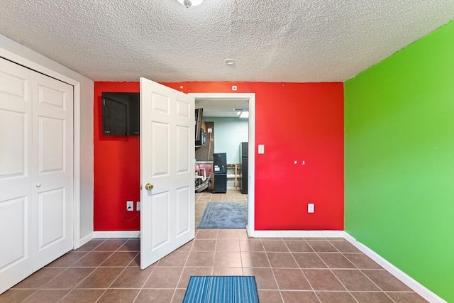 interior space featuring black fridge, a closet, a textured ceiling, and dark tile patterned floors