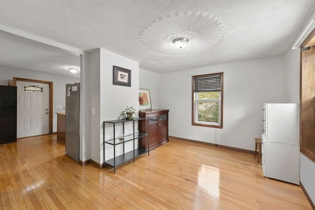 corridor featuring light hardwood / wood-style floors and a textured ceiling