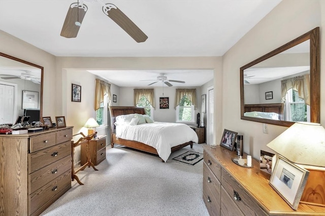 bedroom featuring light colored carpet, ceiling fan, and multiple windows