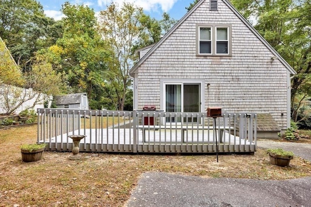 rear view of house featuring a deck and a shed