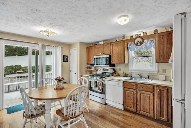 kitchen featuring sink, stainless steel appliances, a textured ceiling, and light hardwood / wood-style floors