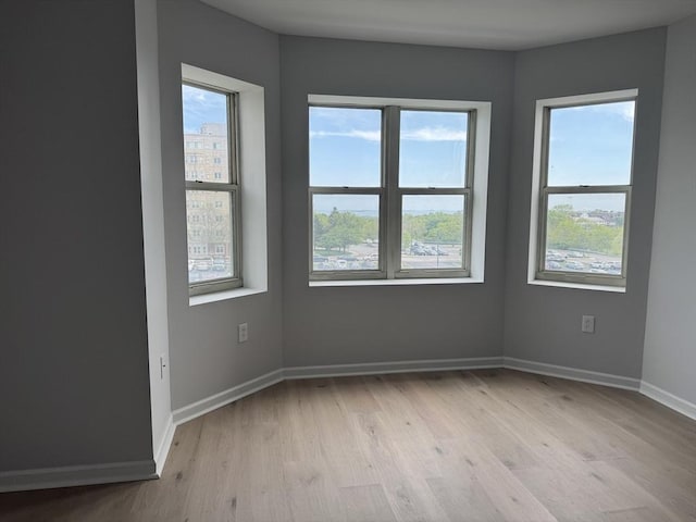 unfurnished room featuring plenty of natural light, light wood finished floors, and baseboards