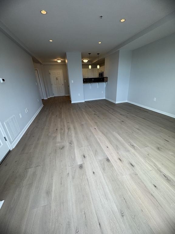 unfurnished living room featuring wood finished floors, baseboards, and recessed lighting