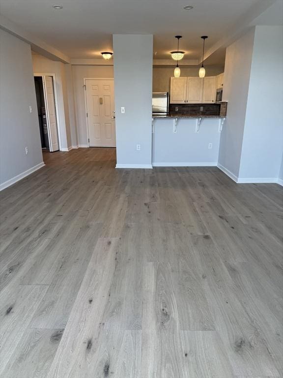 unfurnished living room featuring wood finished floors and baseboards