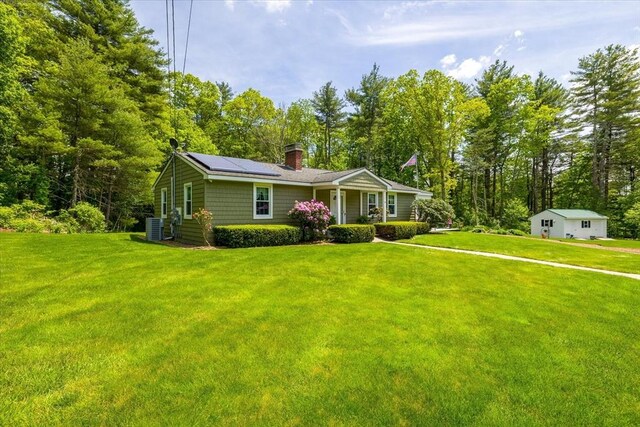 9 Treadwell Ter, Spencer, MA 01562 - view of front of house with roof mounted solar panels, central air condition unit, a front yard, and a chimney