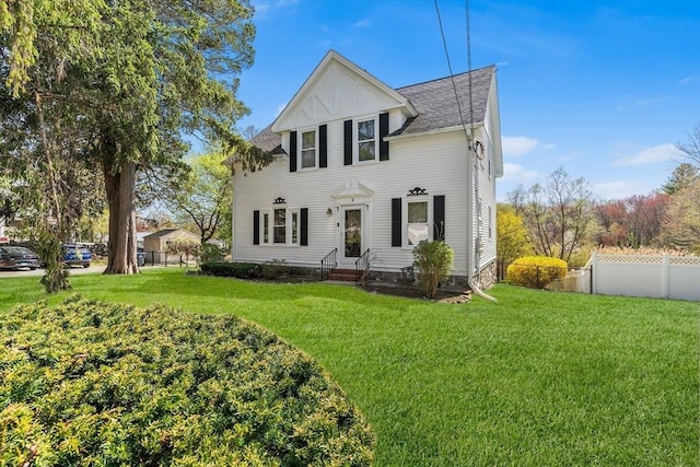 view of front of property with fence, a shingled roof, entry steps, and a front lawn