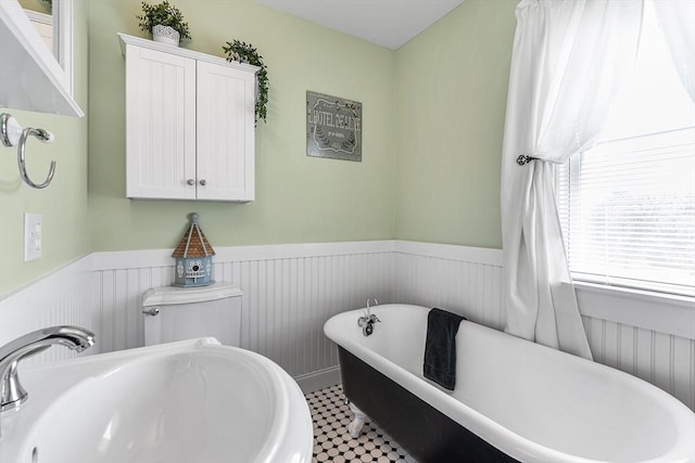 bathroom featuring a sink, a soaking tub, and wainscoting