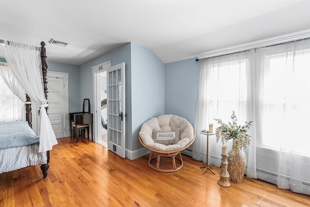 living area featuring baseboards, visible vents, and light wood finished floors
