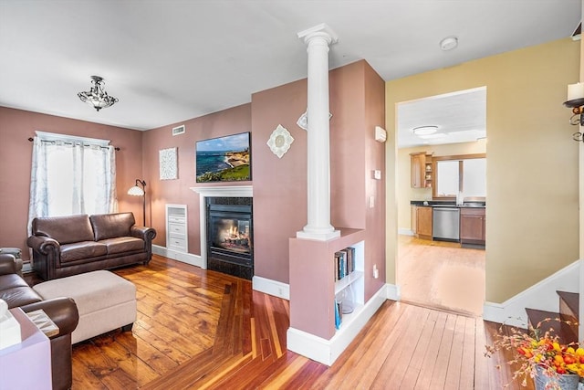 living room with visible vents, decorative columns, hardwood / wood-style flooring, and a premium fireplace