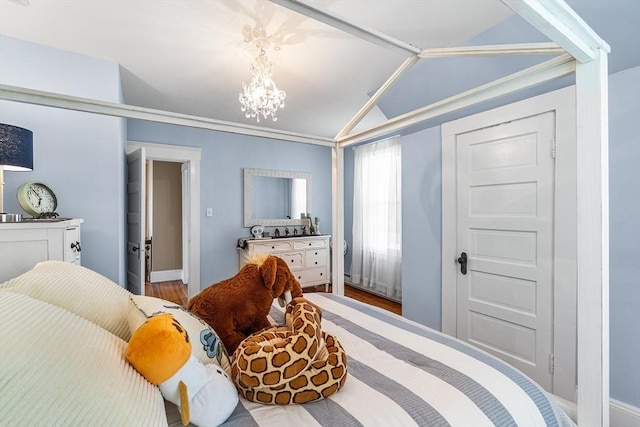 bedroom with an inviting chandelier, baseboards, wood finished floors, and vaulted ceiling