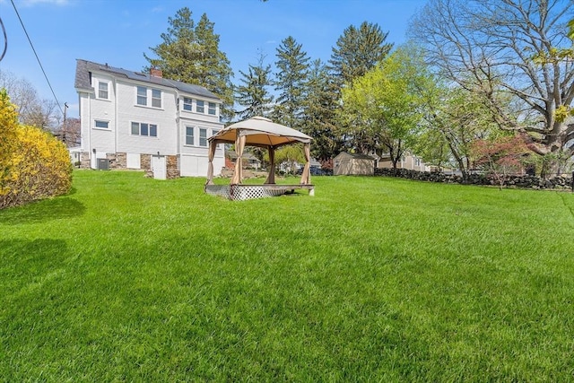 view of yard with a gazebo, an outbuilding, central AC, and a storage shed