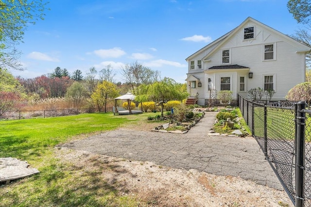 rear view of property with a lawn, a gazebo, and fence