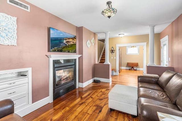 living room featuring visible vents, decorative columns, and wood finished floors