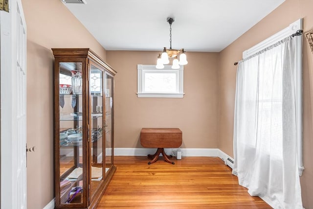 dining space with baseboards, an inviting chandelier, and light wood finished floors